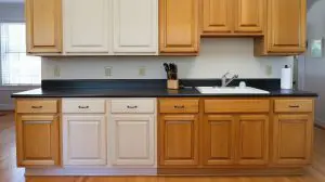 Side-by-side before and after of oak cabinets painted white in NH kitchen