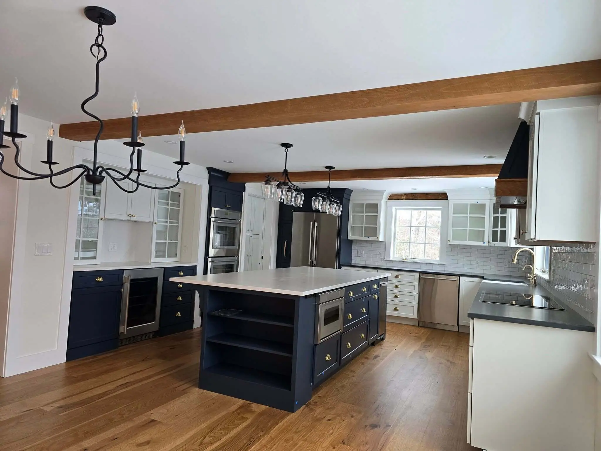 Two-tone cabinet painting in Sunapee NH kitchen with navy island and white cabinets 13 words. Trim to "Cabinet painting in Sunapee NH kitchen with navy island and white cabinets" (12 words) if you want it tighter.Gallery page: Two-tone kitchen with navy blue island white cabinets and exposed wood beams