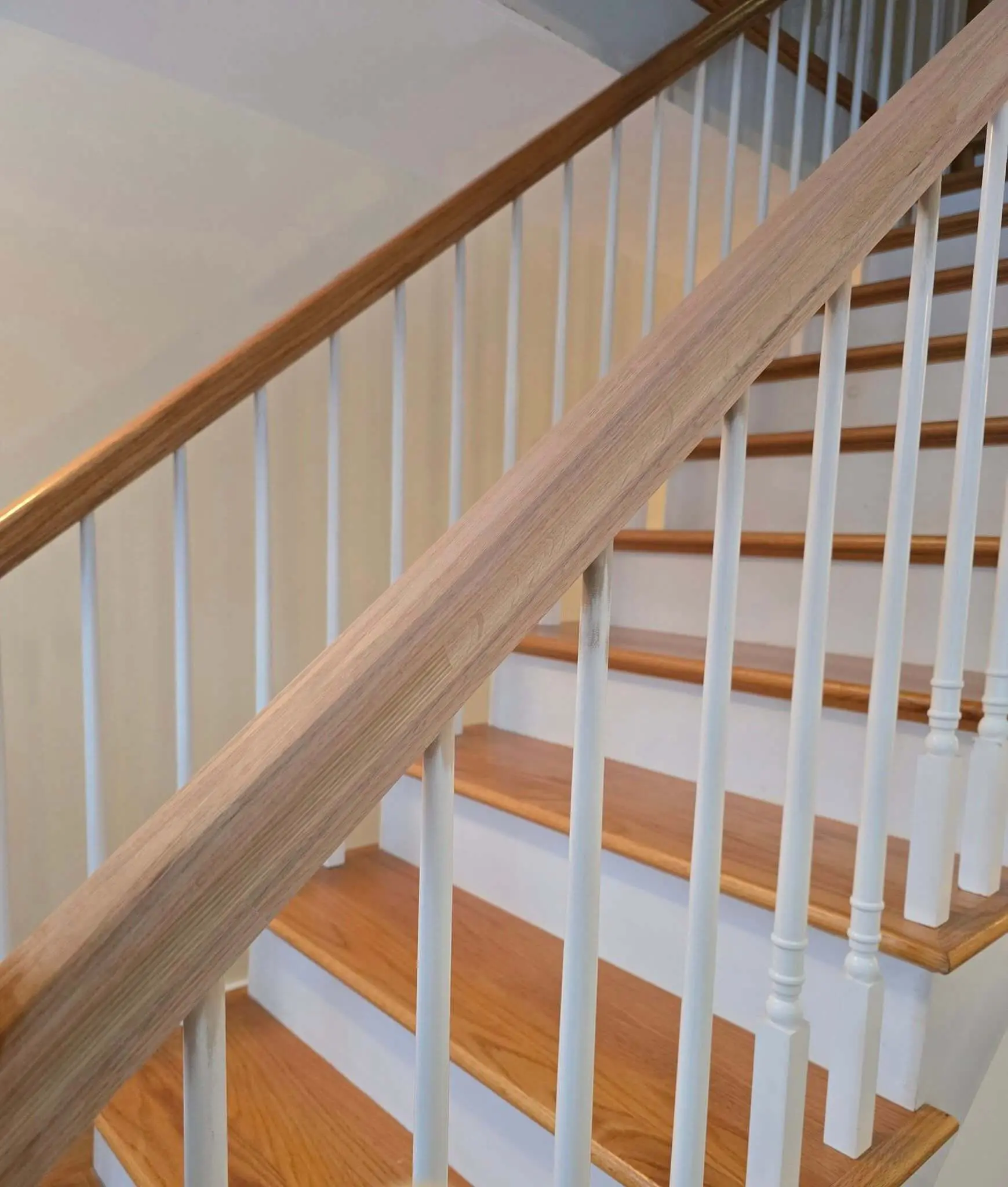 Painted staircase detail with light oak handrail and white spindles