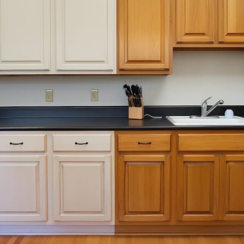 Side-by-side before and after of oak cabinets painted white in NH kitchen