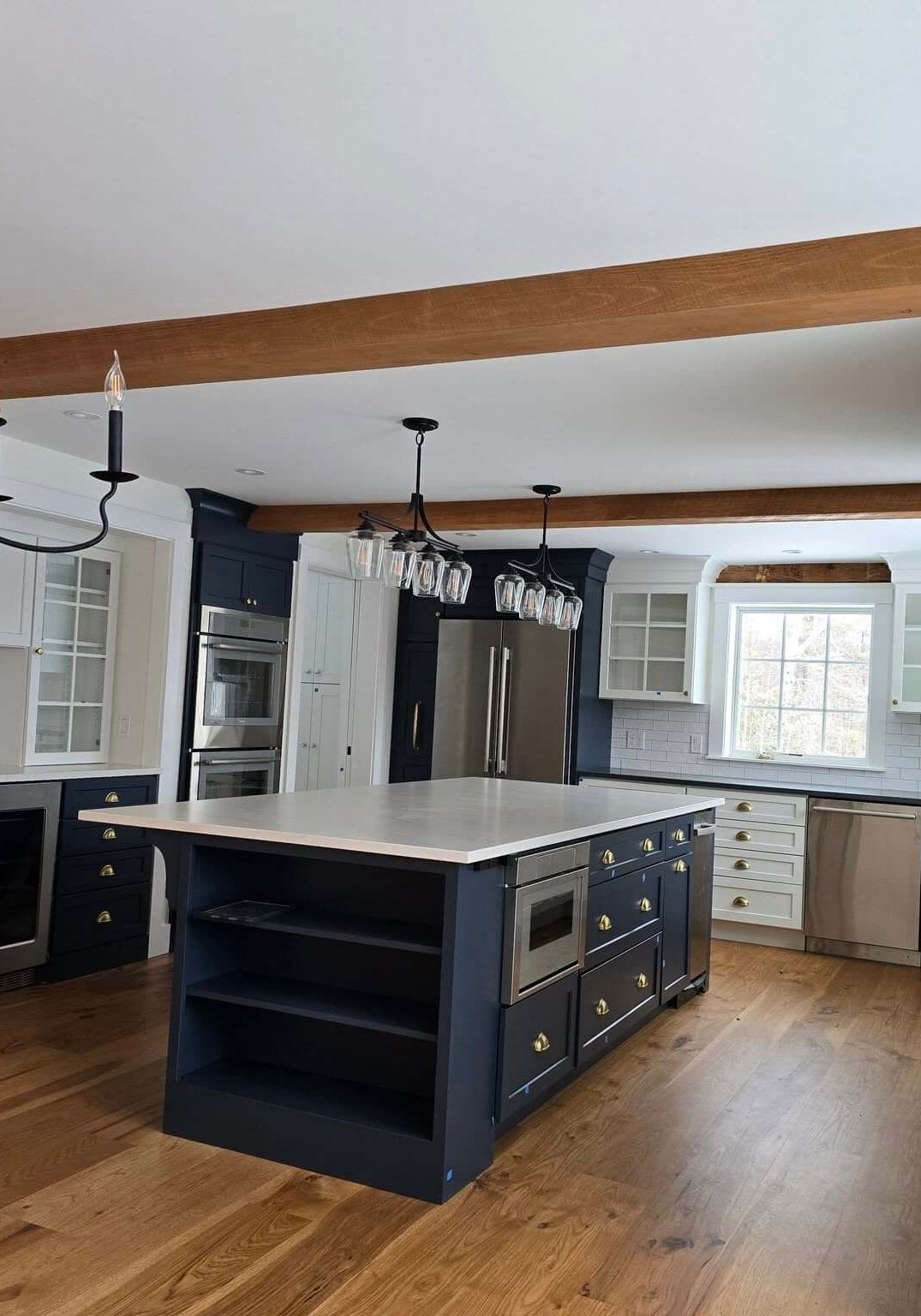 Two-tone cabinet painting in Sunapee NH kitchen with navy island and white cabinets 13 words. Trim to "Cabinet painting in Sunapee NH kitchen with navy island and white cabinets" (12 words) if you want it tighter.Gallery page: Two-tone kitchen with navy blue island white cabinets and exposed wood beams